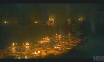 Тем временем Рейнира держит на Драконьем Камне военный совет, стоя над Расписным столом Эйгона Завоевателя. Видим Рейнис в доспехах и Темную Сестру у края стола.